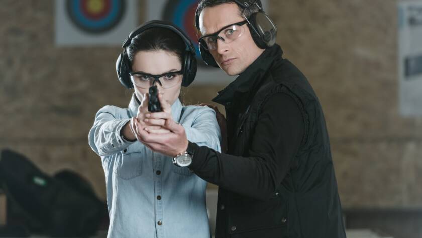 A woman holding a 9mm handgun at a shooting range for self-defense practice.