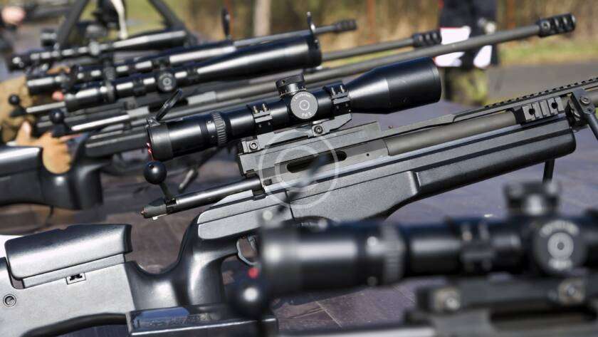 Shooter practicing long-range precision aiming with a rifle.