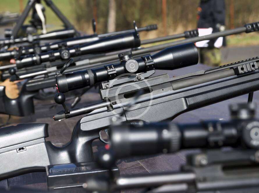 Shooter practicing long-range precision aiming with a rifle.